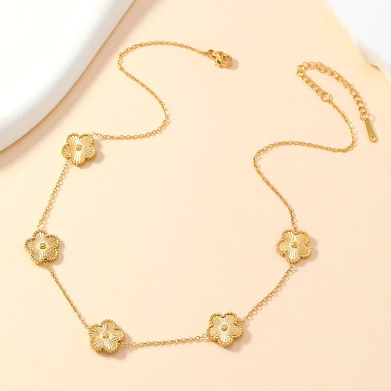  a gold necklace with multiple golden clover-shaped links. on a beige background