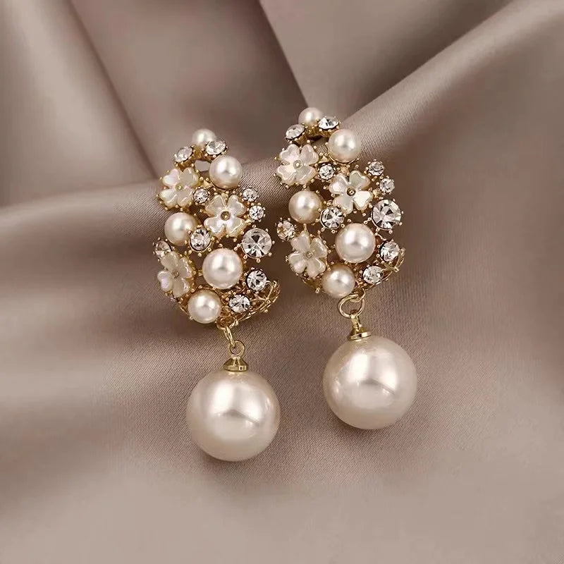 Pair of pearl earrings with gold accents on a beige fabric background