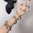 Hand wearing multiple silver rings and bracelets with a black sculpture in the background