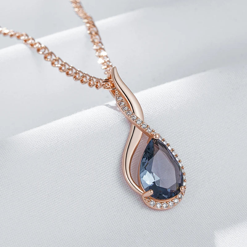 Rose gold necklace with a blue teardrop pendant on a white background