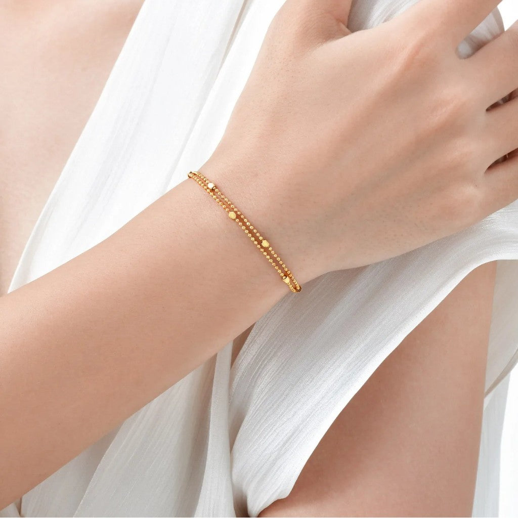 Gold bracelet on a person's wrist with a white fabric background