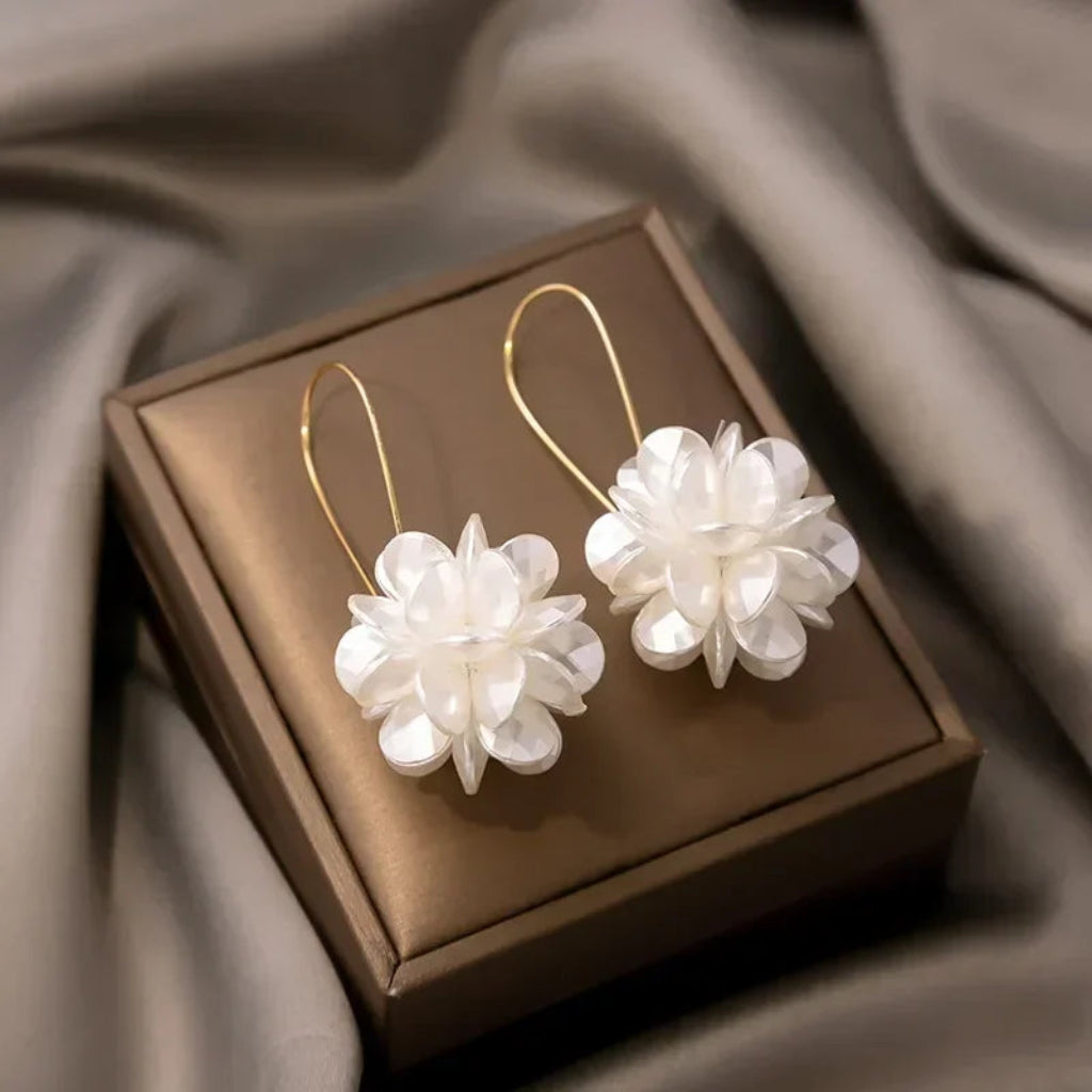 Pair of floral earrings on a brown jewelry box with a soft fabric background