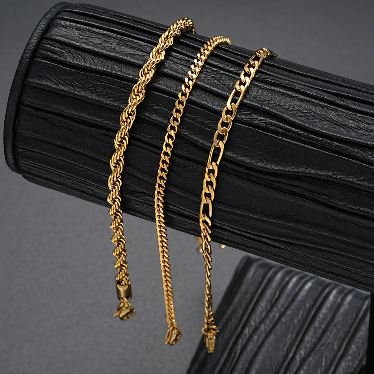 3gold chains on a black textured surface