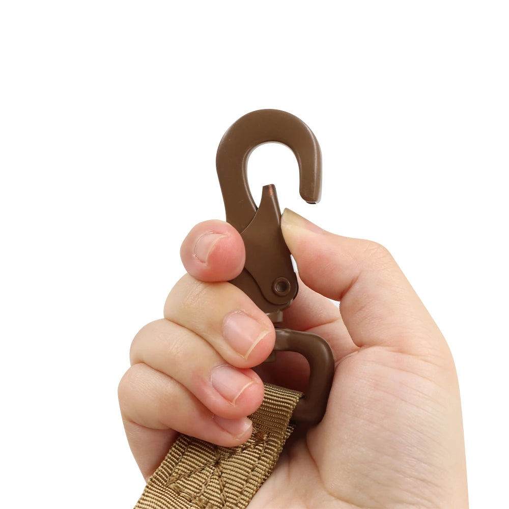 Hand holding a brown plastic hook with a strap on a white background
