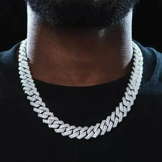 Close-up of a person wearing a Silver  Cuban link chain necklace on a black background