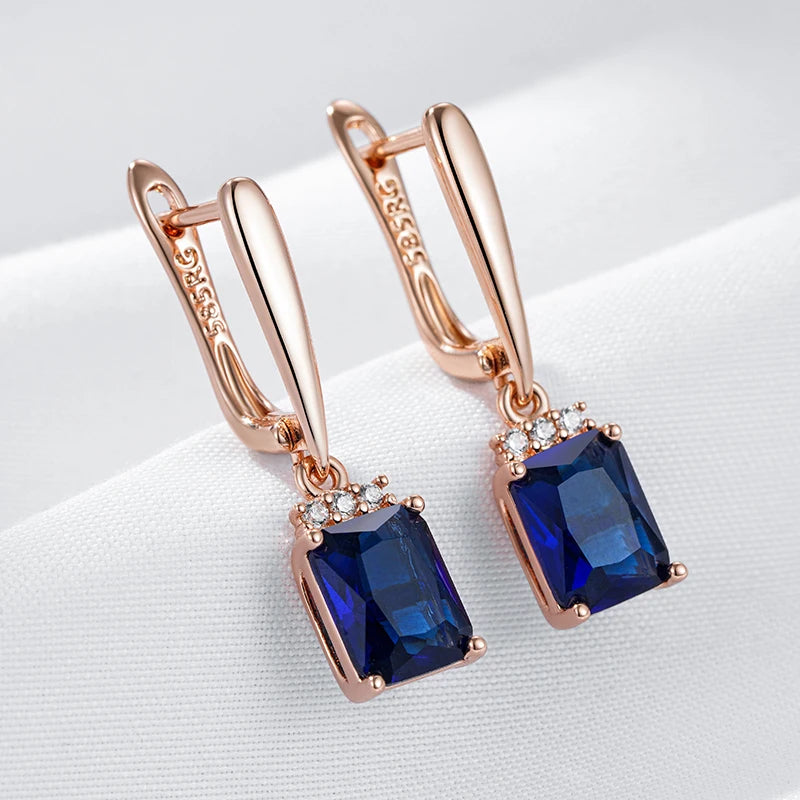 Rose gold earrings with blue gemstones on a white background
