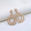 Pair of Gold-plated, double teardrop dangle earrings with a textured, rhinestone-encrusted finish. 