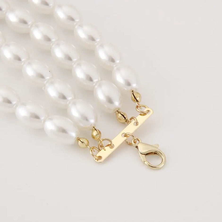 Pearl necklace with a gold clasp on a light gray background