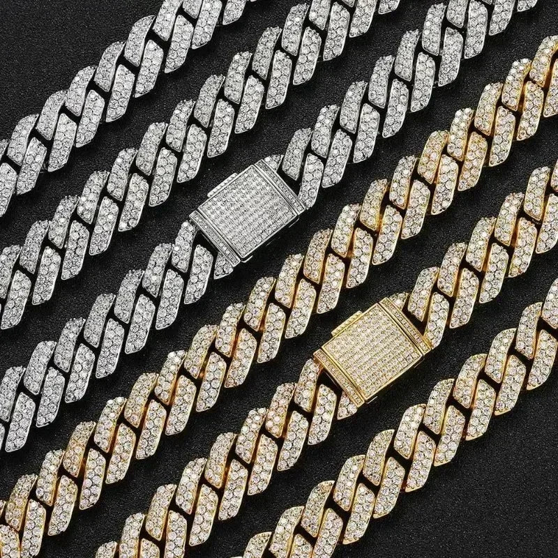 Two diamond, silver, and gold Cuban link chain necklaces, one gold and one silver, on a black background.