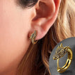 Gold dragon-shaped hoop earrings worn by a person with close-up inset.