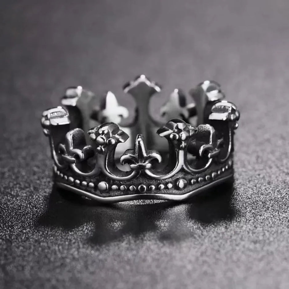 Silver crown-shaped ring on a dark textured surface