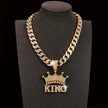Gold chain necklace with 'KING' pendant on a black stand