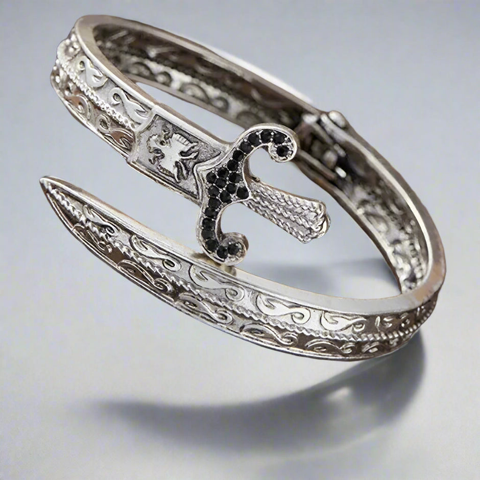 Silver bracelet with intricate designs on a wooden surface
