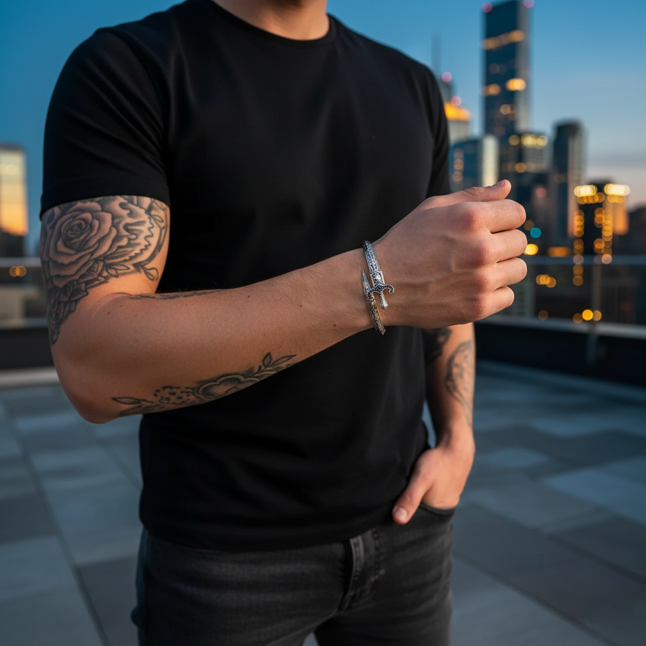 Person wearing a black t-shirt with tattoos on arms and hands, standing on a rooftop with city skyline in the background.