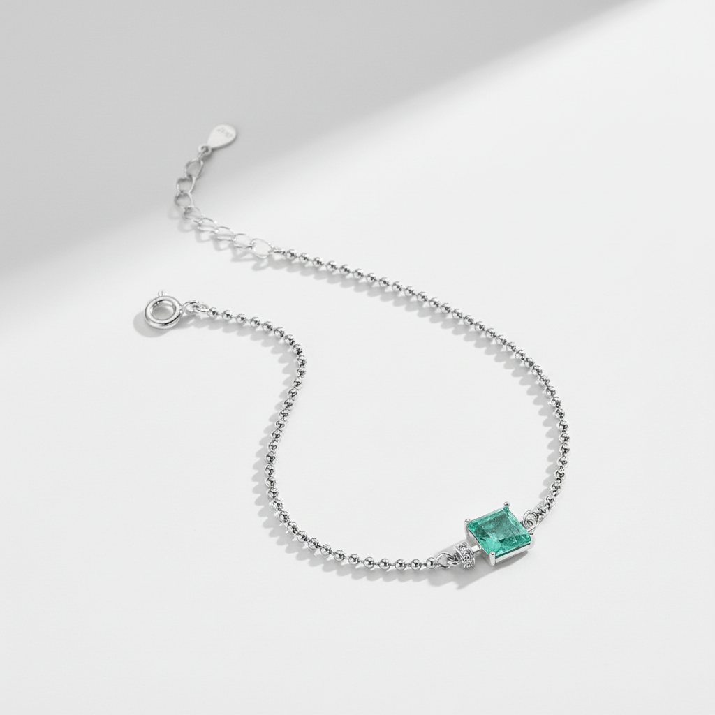 Silver bracelet with a green gemstone on a light gray background