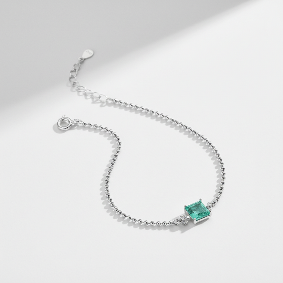 Silver bracelet with a green gemstone on a light gray background