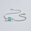 Silver bracelet with a green gemstone on a light gray background