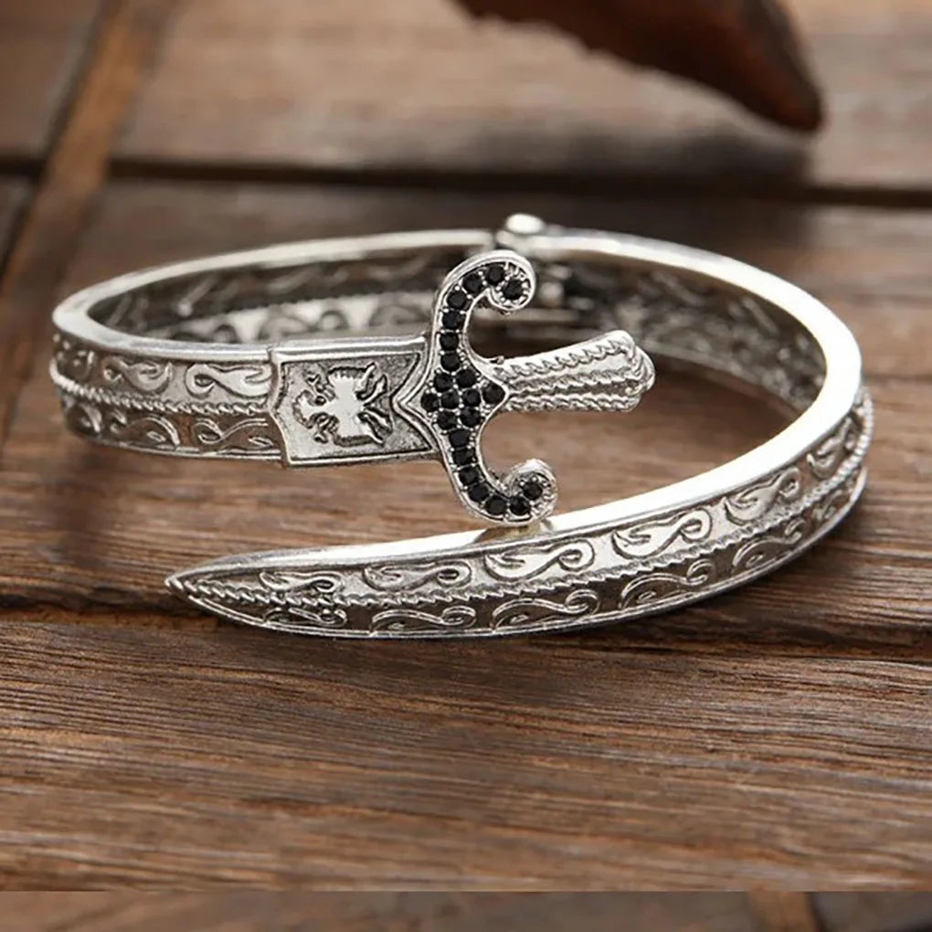 Silver bracelet with intricate designs on a wooden surface