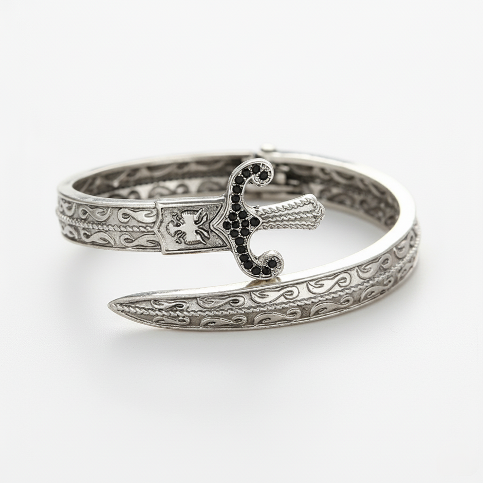 Silver bracelet with intricate design and black gemstones on a white background