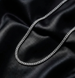 Silver chain cubun link necklace on black satin fabric