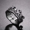 Silver crown-shaped ring on a textured gray background