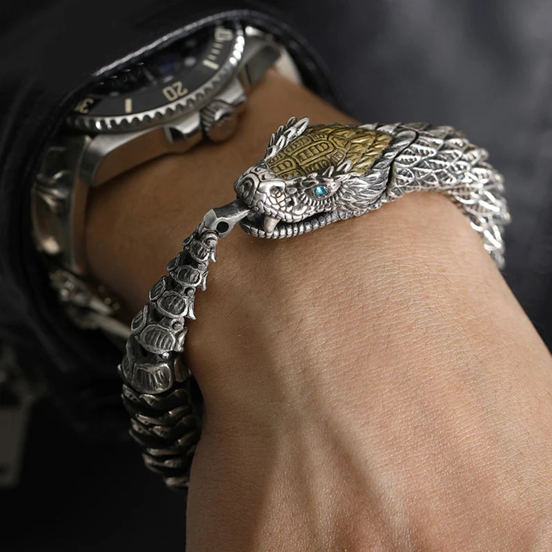 Silver dragon bracelet on a wrist with a watch in the background