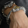 Silver dragon bracelet on a wrist with a watch in the background
