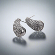 Silver earrings with a textured design on a reflective surface