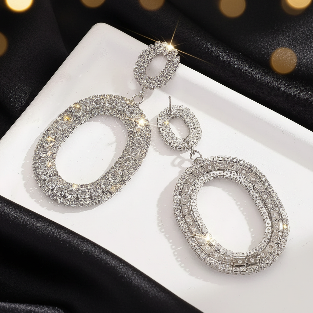 Silver hoop earrings with rhinestones on a white surface