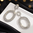 Silver hoop earrings with rhinestones on a white surface