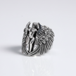 Silver ring with angel and wing design on a light gray background