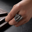 Hand wearing a silver ring with an eagle design on a dark background