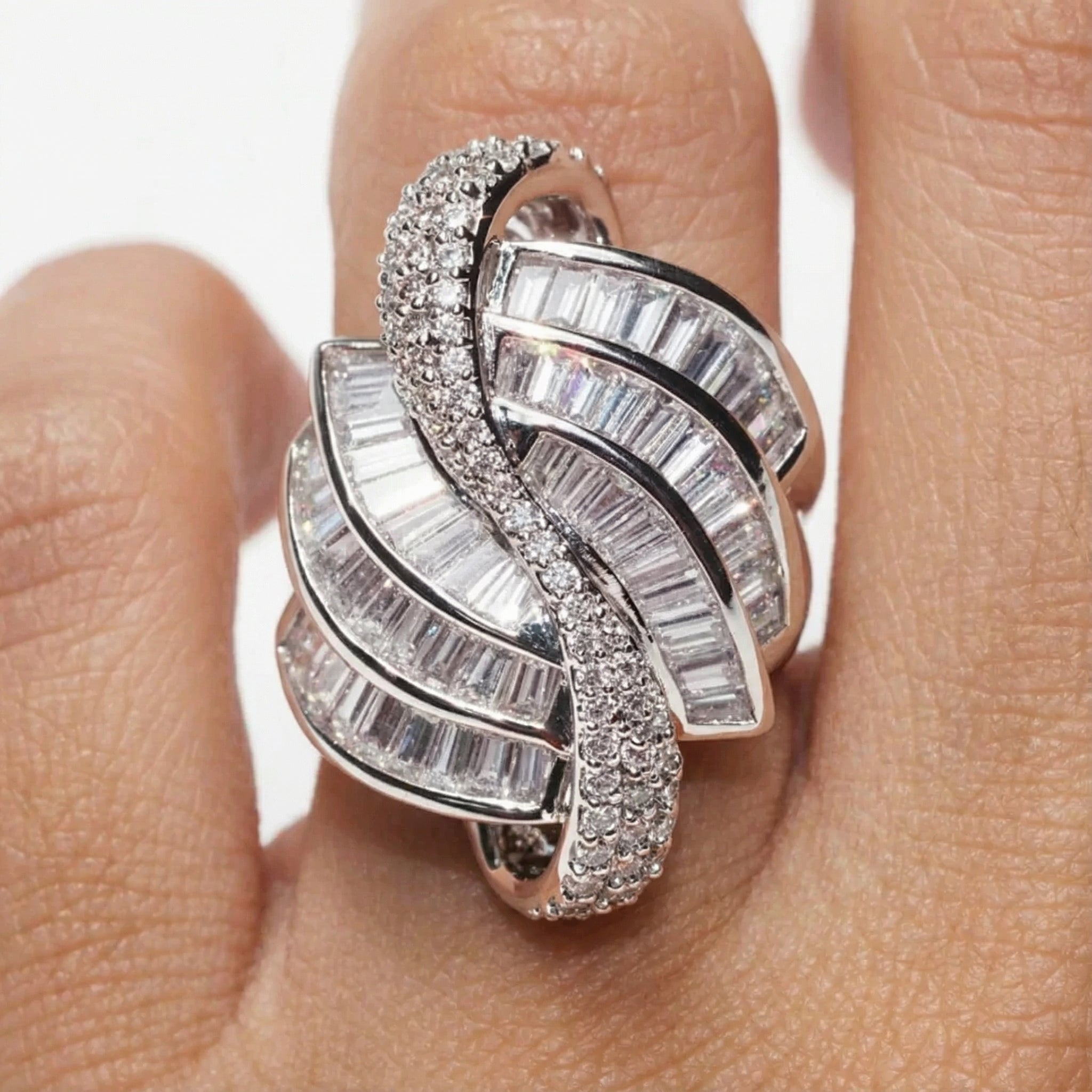 Silver ring with diamond accents on a finger against a neutral background
