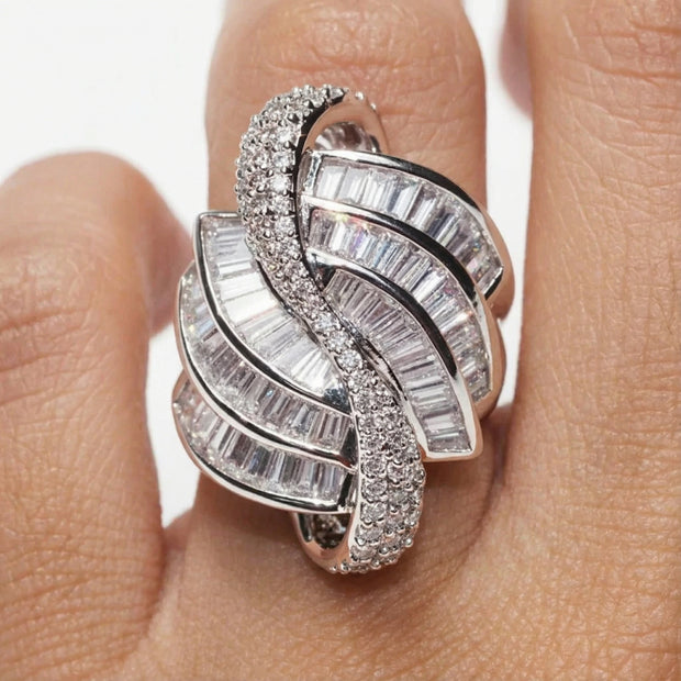Silver ring with diamond accents on a finger against a neutral background