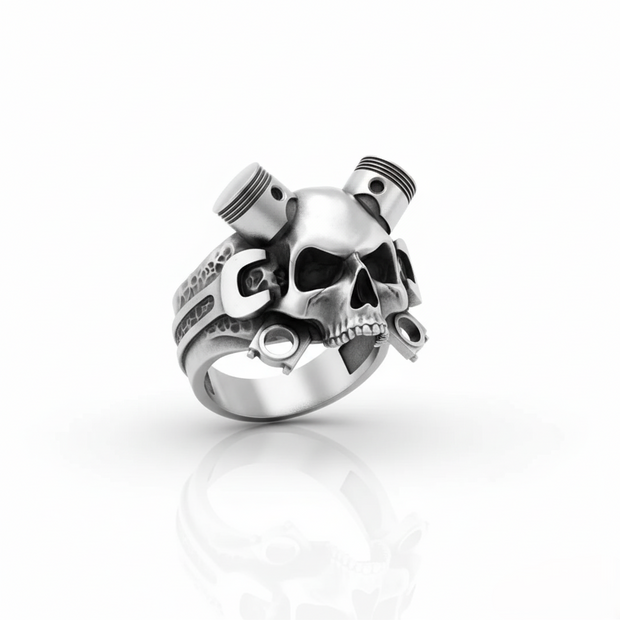 Silver ring with skull and piston design on a white background
