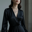 Woman wearing a black dress and snake-shaped necklace against a neutral background