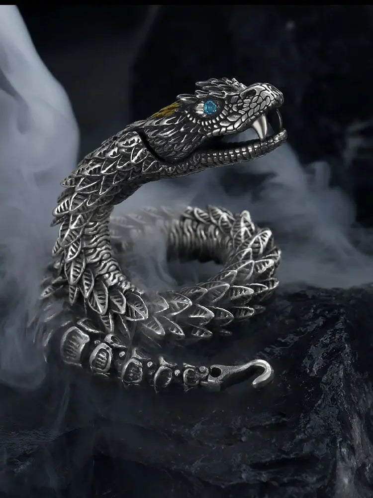 Silver snake-shaped cuff with a blue gemstone on a dark background