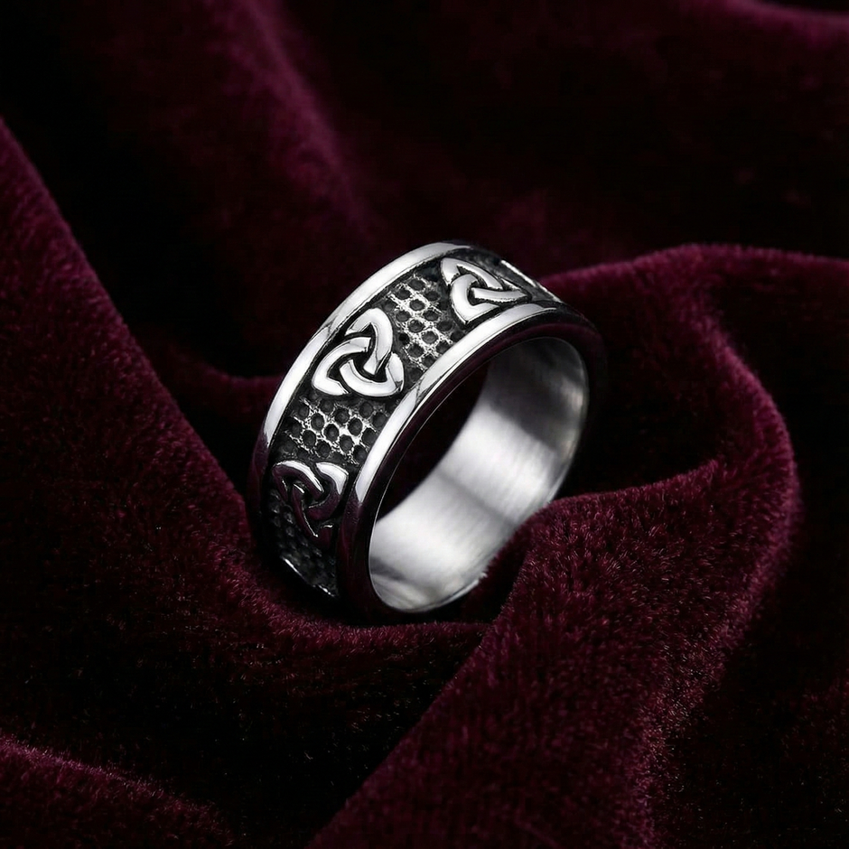 Silver trinity knot ring with intricate design on a dark red fabric background