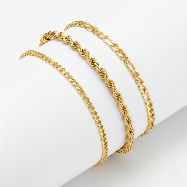 3 gold chains on a light gray surface with a white background