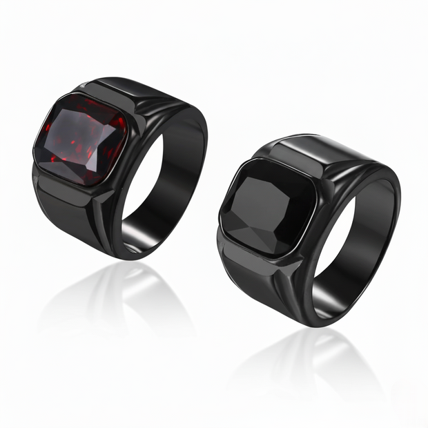 Two black rings with a red gemstone on a white background