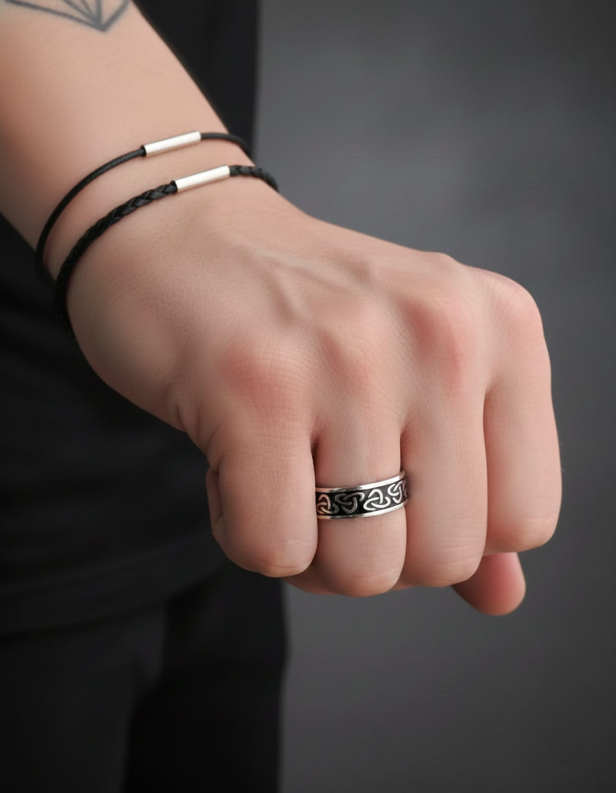 Hand wearing a Viking ring, sterling silver with an intricate design on a dark background