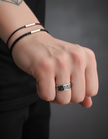 Hand wearing a Viking ring, sterling silver with an intricate design on a dark background