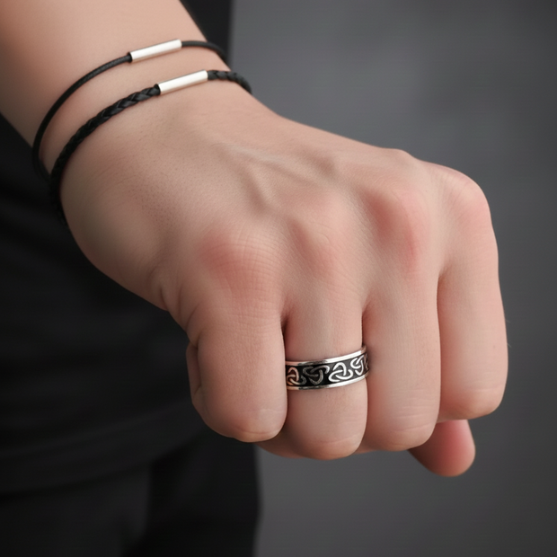 Hand wearing a Viking ring, sterling silver with an intricate design on a dark background