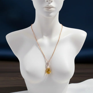 Mannequin wearing a necklace with a yellow pendant against a dark background