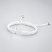 White braided bracelet with a silver cross charm on a light gray background