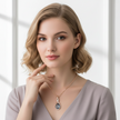 Woman wearing a necklace with a teardrop pendant against a neutral background