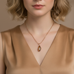 Woman wearing a gold necklace with a pendant against a neutral background