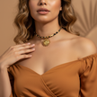 Woman wearing a gold necklace with a sun design against a beige background