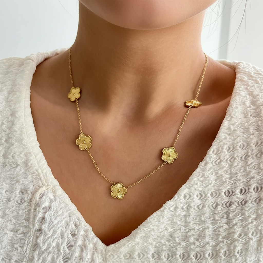  a gold necklace with multiple golden clover-shaped links. worn by a person against a neutral background
