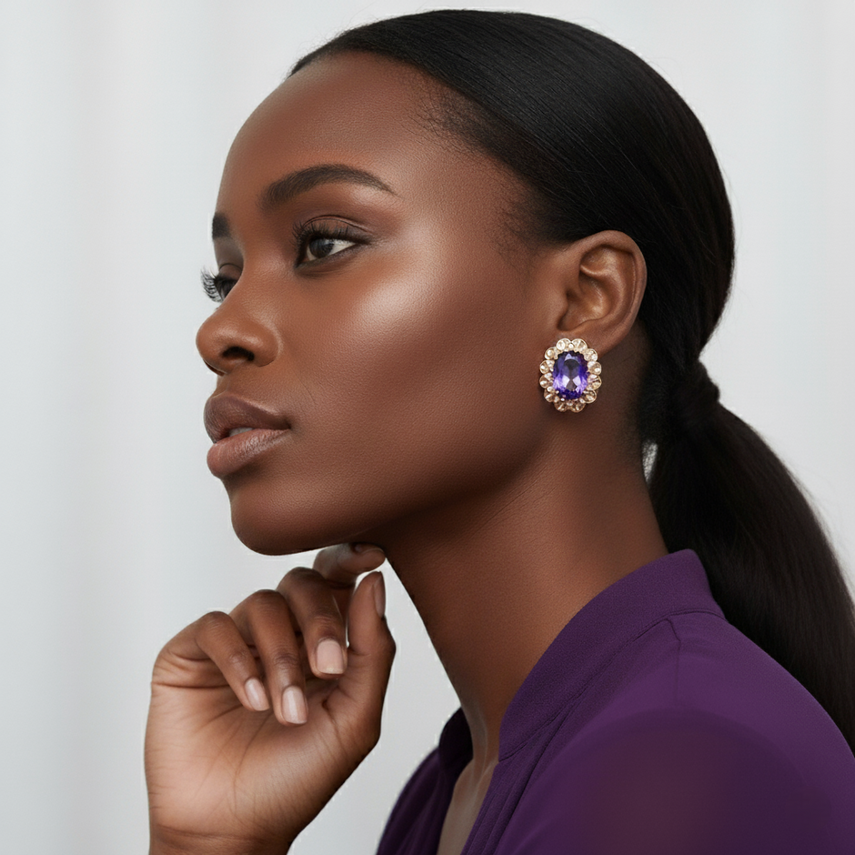 A woman wearing a purple earring with a gemstone on a plain background
